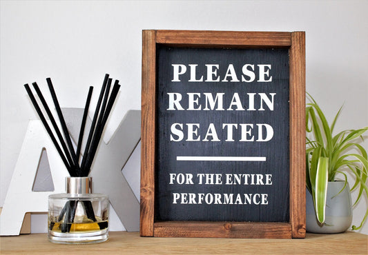 Please Remain Seated - Bathroom Sign
